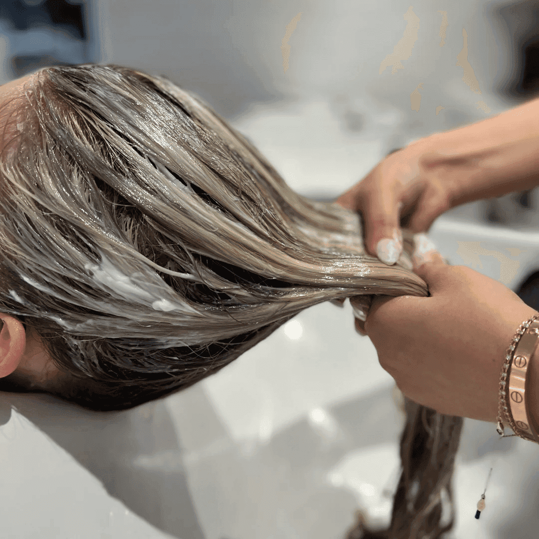 Hair treatment being applied to a customer's hair in a salon setting.